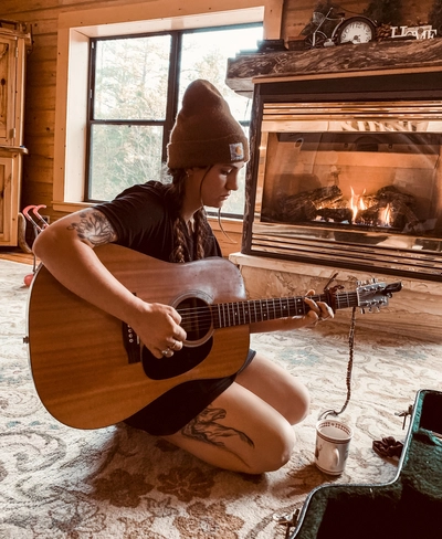 Ellanora DellErba with a guitar and hat.